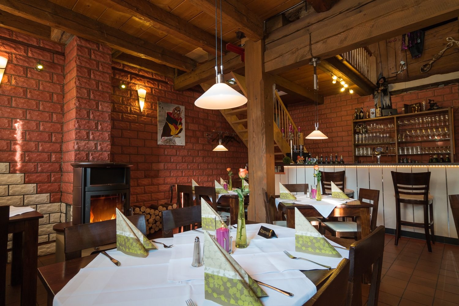 Gastraum mit Backsteinwand, gedeckten Tischen und Holzdecke