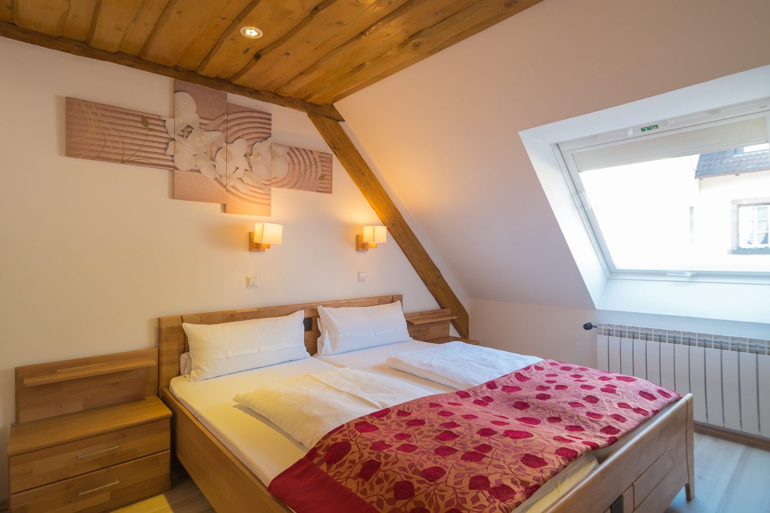 Zimmer unter dem Dach mit Dachfenster und Doppelbett